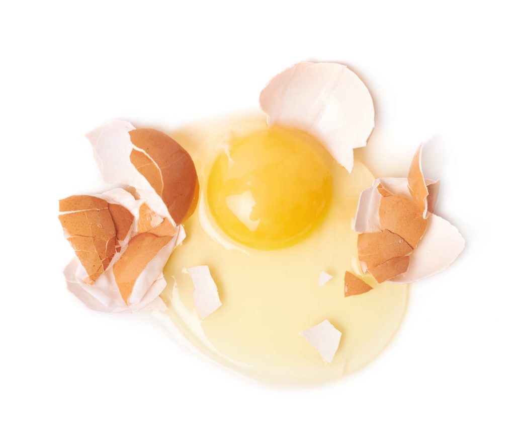 Cracked raw chicken egg and broken shell composition, isolated over the white background